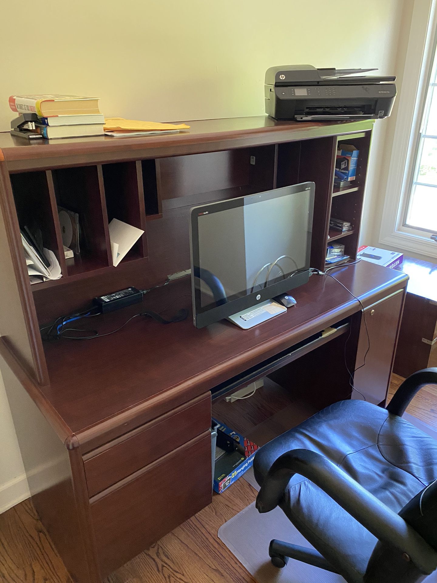 Dark brown desk with drawers and desk chair.