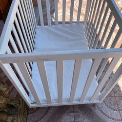 Wooden crib in good condition, including its mattress (still wrapped in plastic). The frame features three adjustable height settings. It measures 40 