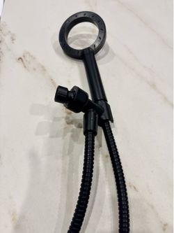 Black handheld shower head with a flexible hose and connection point.