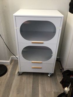 White metal storage cabinet with wood like finish with brass handles