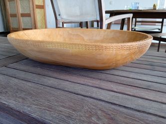 An elongated carved wooden bowl with delicate shell inlay along the inner contour.