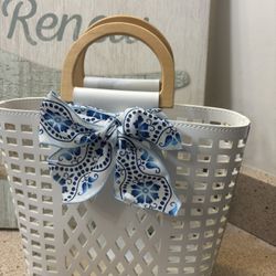 Joy Susan White, grid-patterned tote bag featuring wooden top handles and a blue and white patterned bow accessory.  Excellent Condition. Ready for pi