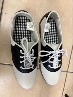 Predictions brand black and white saddle shoes featuring a classic sock-hop or 50s retro style.