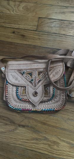 Handcrafted leather crossbody bag with intricate hand-tooled floral and geometric patterns. This tan leather purse has colorful whipstitched edges and