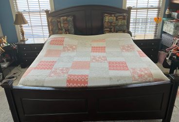 A queen bed made of solid wood and two side tables.
