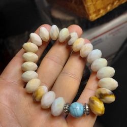 stretch beaded bracelet featuring polished oval-shaped white beads, variegated brown and white jasper beads, a turquoise bead, and silver-tone spacer 