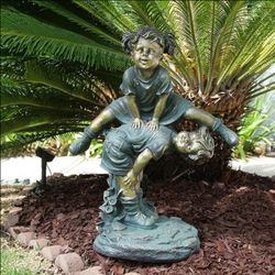 Girl jumping over Boy statue Yard Art