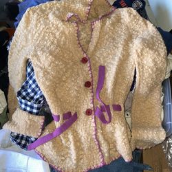 Anna Sui knit cardigan featuring a textured, popcorn-like knit in a warm beige or mustard yellow hue. It is distinguished by its vibrant purple or bur
