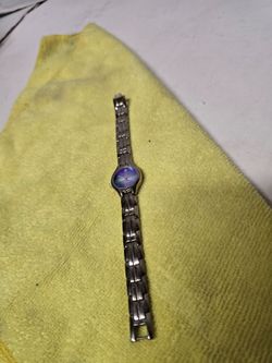 Rumours women's wristwatch features a silvertone link band and a iridescent blue face.