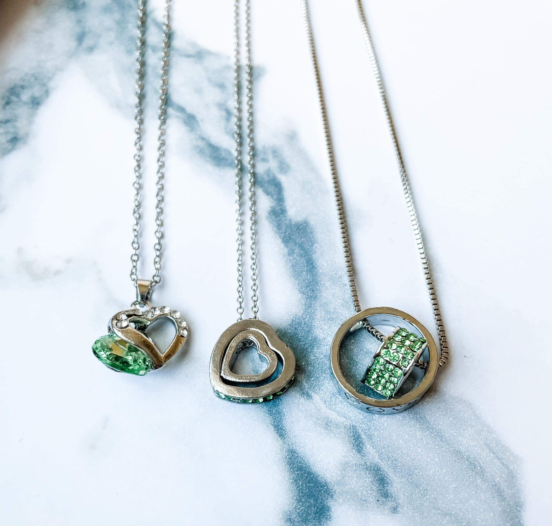 Three silver necklaces with green gemstones