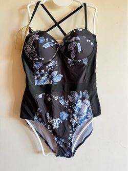 Sleek black one-piece swimsuit with blue and white floral print. Built-in cups and adjustable crisscross straps. Feminine floral pattern for stylish b