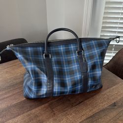 Coach Voyager Duffle Bag in a black and blue plaid pattern.
