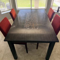Modern dining table with 4 matching red upholstered chairs.