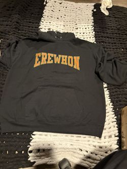 This is a black Erewhon x Champion x Pizzaslime pullover sweatshirt hoodie with an orange and green logo