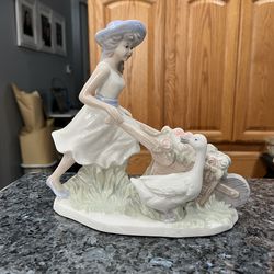 Vintage Porcelain Figurine “ Girl pushing a wheel barrel with flowers and a duck”.  Side approximately 7 1/2 inches tall and 8 inches long.  Preowned 