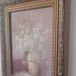 Pretty framed art piece. Has a dark red/burgundy background with pink and gold flowers and scrollwork. Black frame with gold trim and a patterned mat.