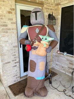 6.5-foot-tall Gemmy Star Wars Mandalorian with Grogu Christmas Inflatable featuring Din Djarin holding Grogu and a red holiday ornament