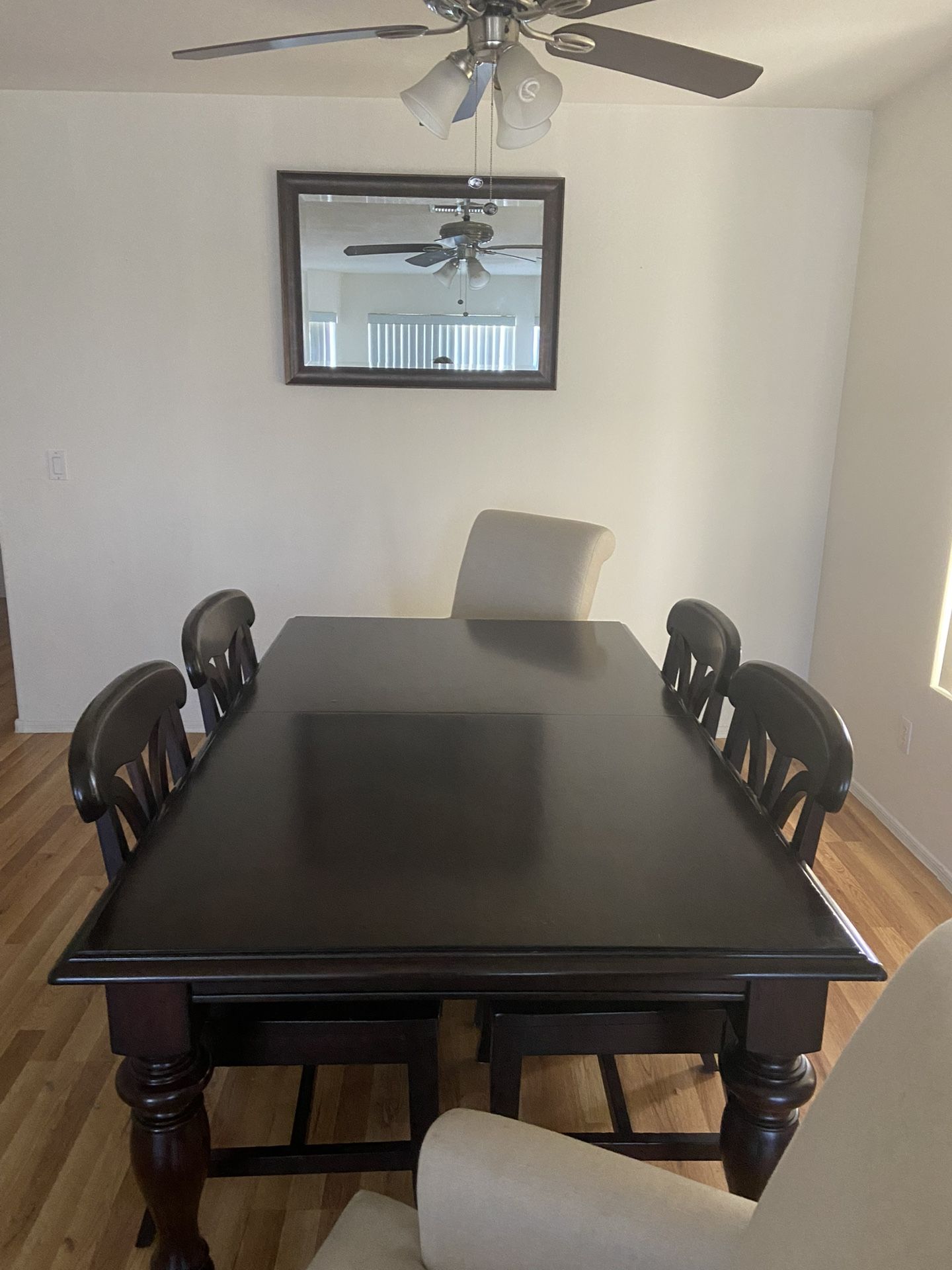 Brown wood dining table 6 chairs with mirrors and wall portraits