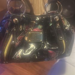 The brand is baby phat it’s black and shiny and has cute flower designs and it’s not too big but not too small so right in the middle