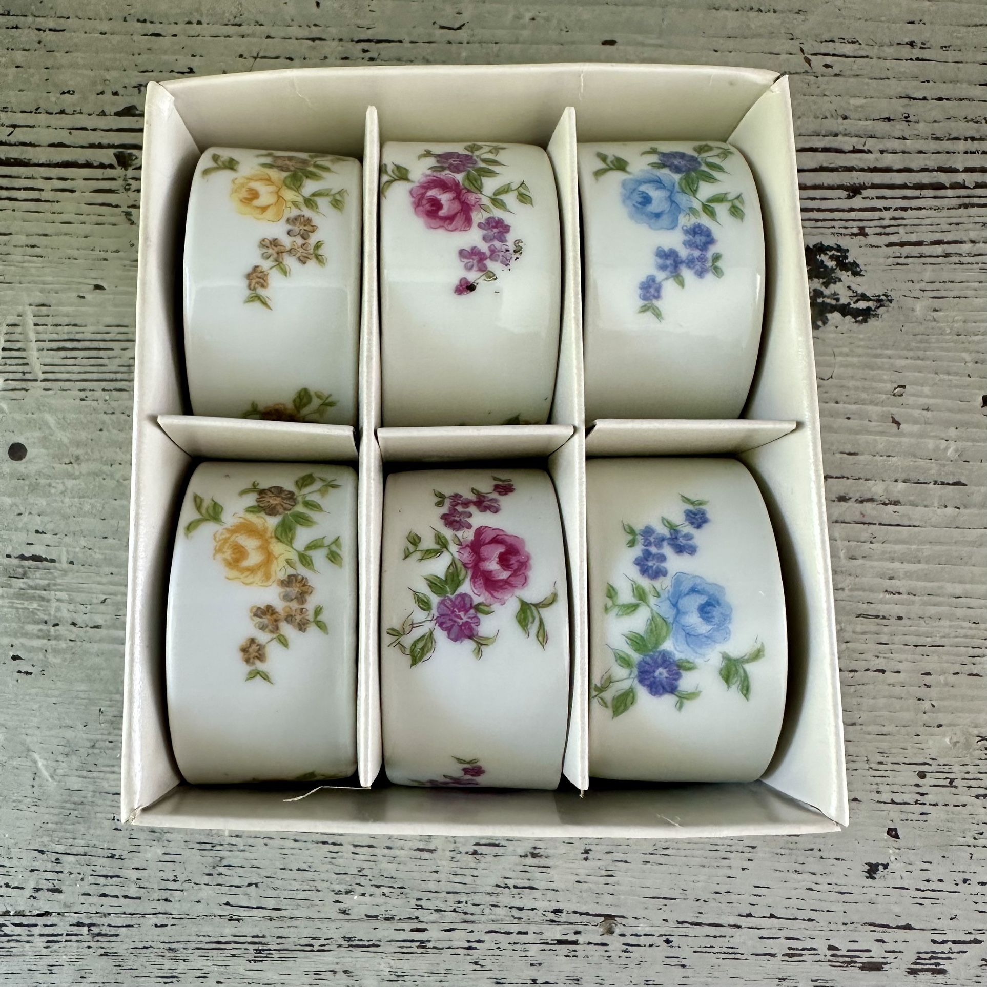 Set of 6 vintage porcelain ceramic floral rose napkin rings Japan Unused in original box. Pink yellow and blue roses 2 of each color.