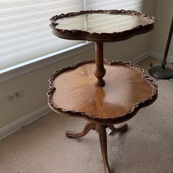 A two-tiered Queen Anne style hardwood side table with glass top.