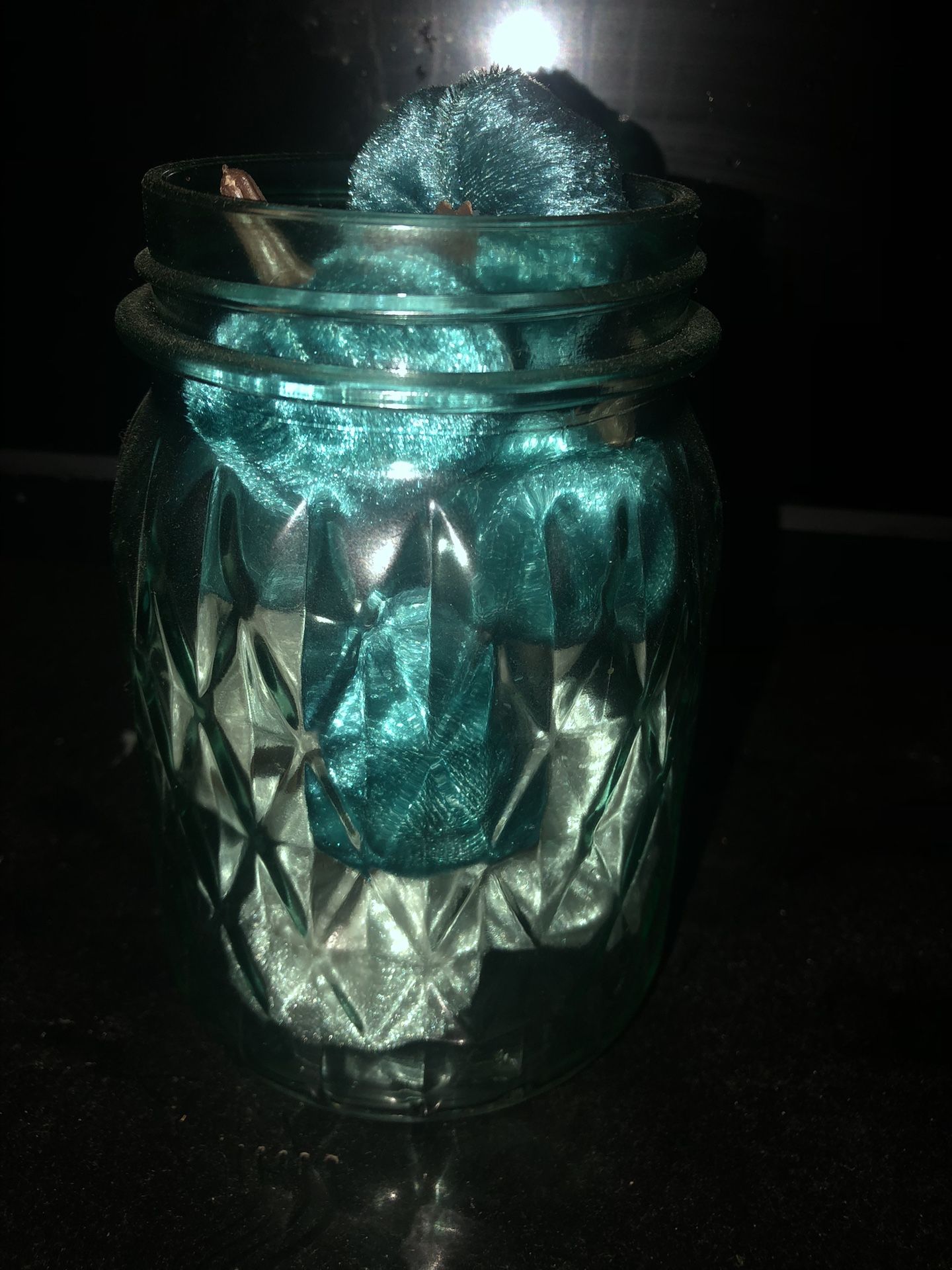 Elegant glass jar filled with teal fabric. Perfect for home decor.