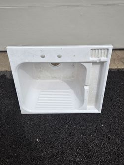 Acrylic laundry sink features a built-in washboard and molded soap dish