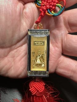 square "Safe Traffic" amulet charm with gold lettering. Charms often feature Chinese knots and tasse