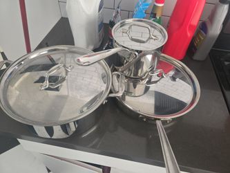 Set of 3 all clad stainless steel pots and pans with lids.