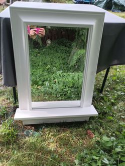 White-framed wall mirror featuring an integrated bottom display ledge.