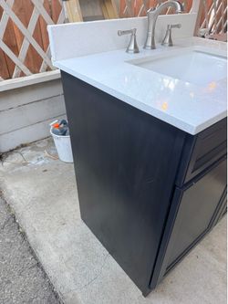 30” Vanity cabinet with stone top and faucet.