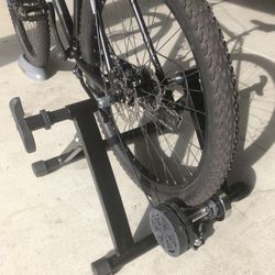 Indoor bicycle trainer with front wheel riser and difficulty control knob.