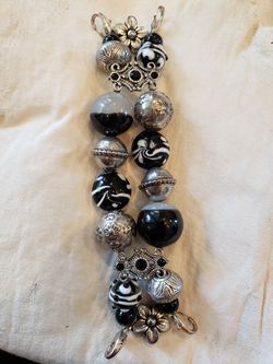 Handmade black and white and silver glass bead bracelet. Bracelet is 6 in long. 1.5 in wide. Four lobster clasps.