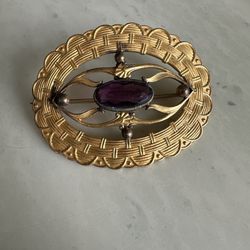 Vintage gold tone oval brooch w/ a central purple stone & ornate design