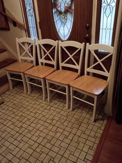 Four white and blonde wooden kitchen chairs