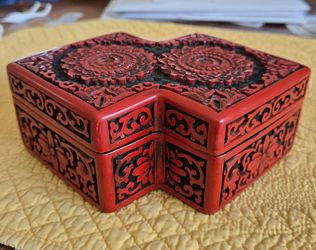 This is a Chinese cinnabar carved red lacquer 8 sided trinket box with lotus floral carvings and a black lacquer interior. 6.5" on longest dimension