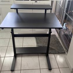 Adjustable black desk that raises and lowers. Includes monitor shelf and bottom shelf for extra storage. Good used condition, sturdy and functional. G