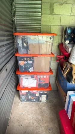 4 Clear Storage Bins with Orange Lids with Halloween decorations and inflatables.
