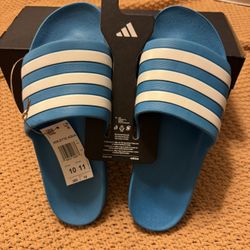 Adidas Adilette Aqua Slides in the colorway Solar Blue/Cloud White/Solar Blue, with the product code FY8047. 