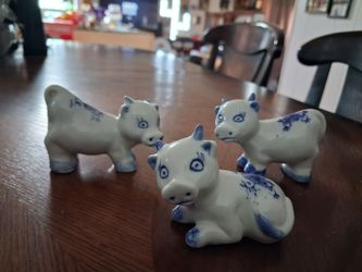 set of three vintage porcelain figurines featuring cows in cobalt blue and white