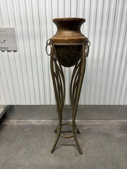 Hollywood Regency style wrought iron pedestal plant stand featuring a curvaceous Roman urn silhouette.