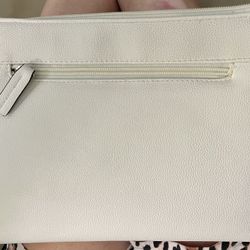 This B. Brentano Vegan Multi-Zipper Crossbody Handbag Purse features a pebbled white exterior with tassel accents and silver hardware. The bag has a r