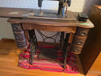 Antique "New Companion" treadle sewing machine with 7 drawers, and a box of new accessories.