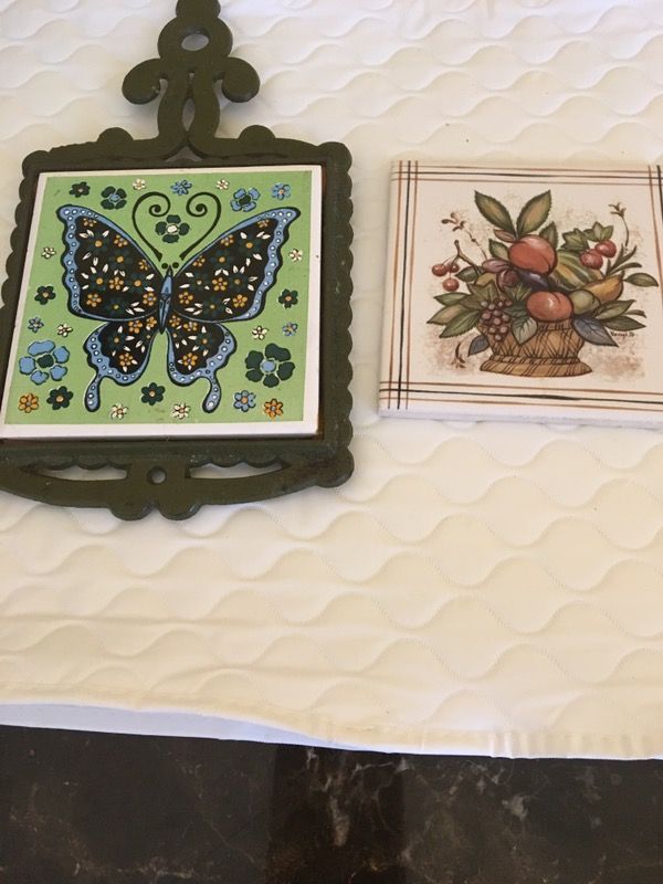 A vintages hot pot holder metal with a piece of tile