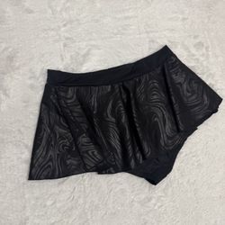 Black skirted shorts with a subtle swirl texture. Designed for comfort with a soft elastic waistband. Versatile piece that pairs well with athletic or