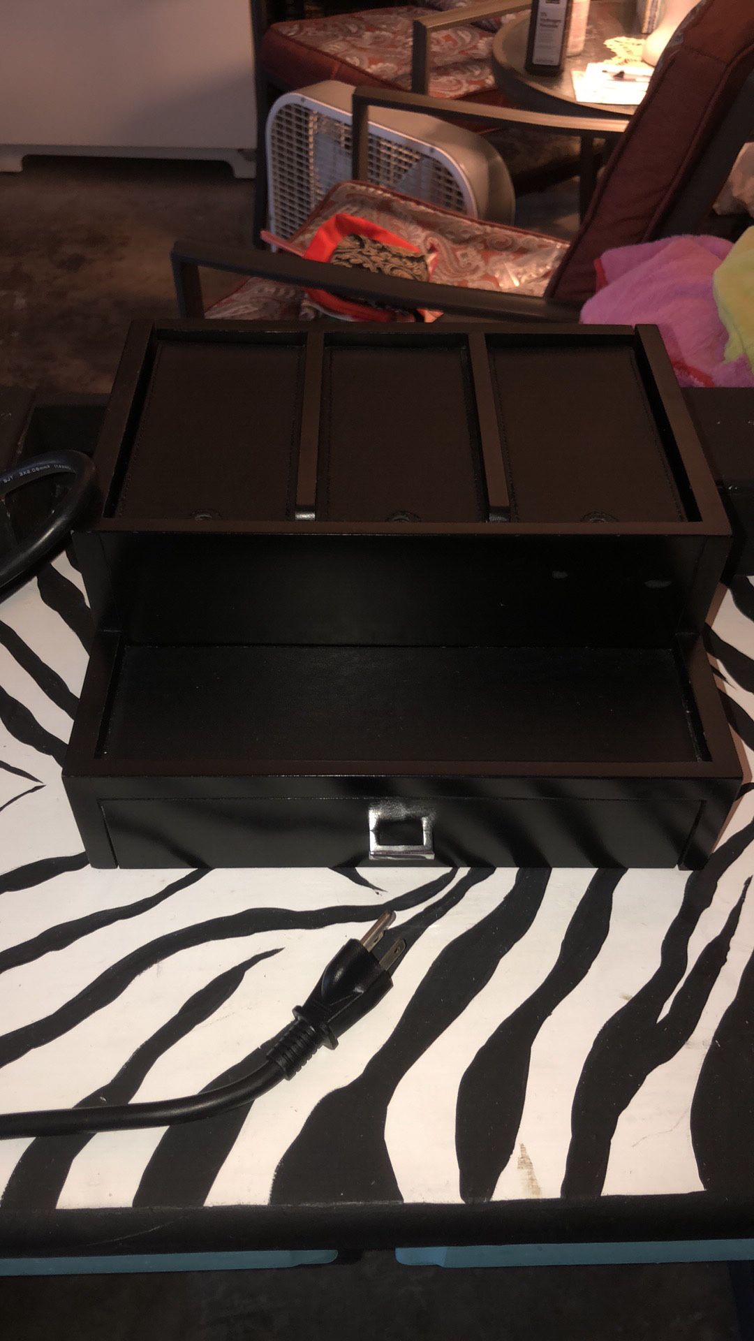 Black wooden piece that holds cell phones on top and opens up to underneath where they connect to charge and it has a drawer that opens too. It makes