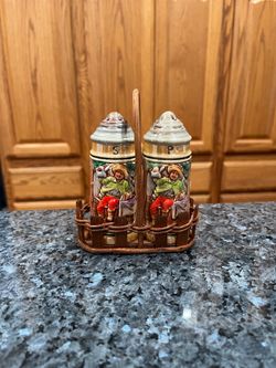 Vintage German Beer Stein Style Ceramic Salt and Pepper Shakers with carrier.  Preowned.  Size approximately 4 inches tall.