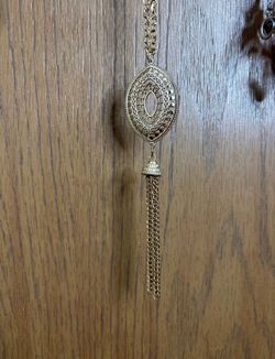 Gold colored necklace with a tassel at the bottom