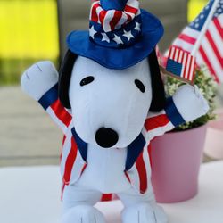 Peanuts Snoopy 4th of July dancing plush doll.  He dances to Yankee Doodle in his patriotic coat and hat waving the US flag.  12” tall.